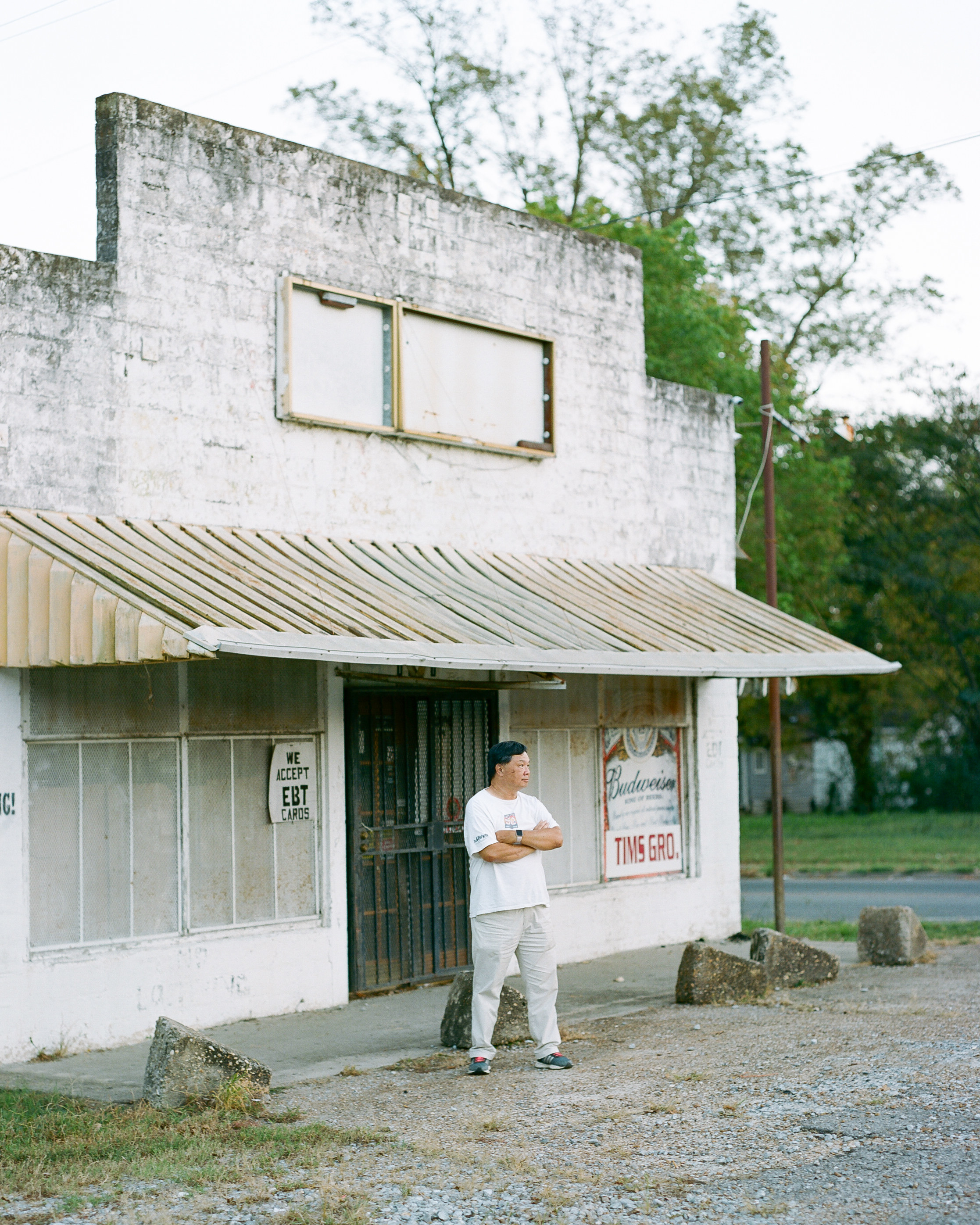 A man stands in front of an abandoned storefront