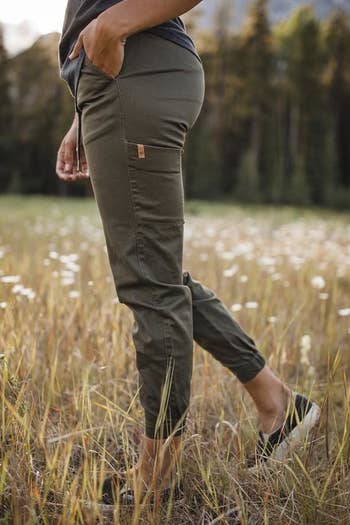 The profile view of a model wearing the joggers with their hand in a side slit pocket and revealing a patch pocket on the back thigh 