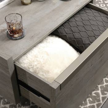 the table with one drawer open revealing folded throw blankets
