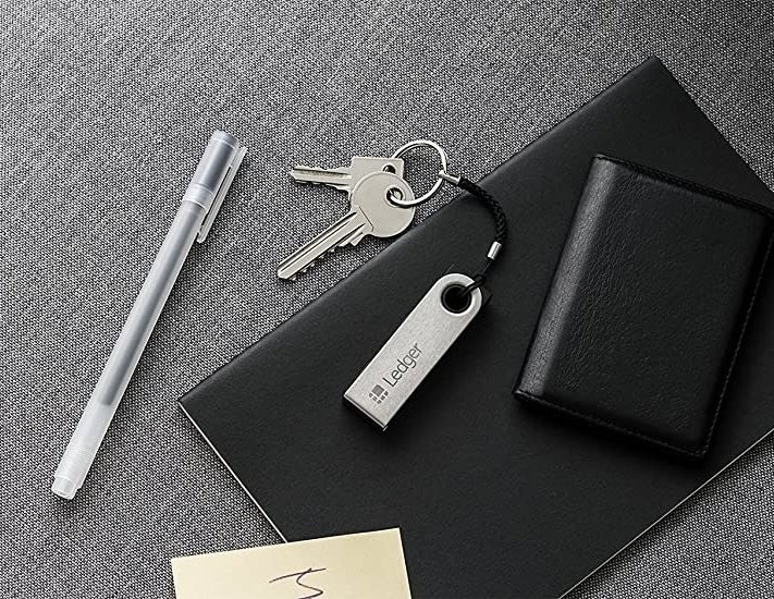 The USB cryptocurrency wallet on a leather notebook next to a pen