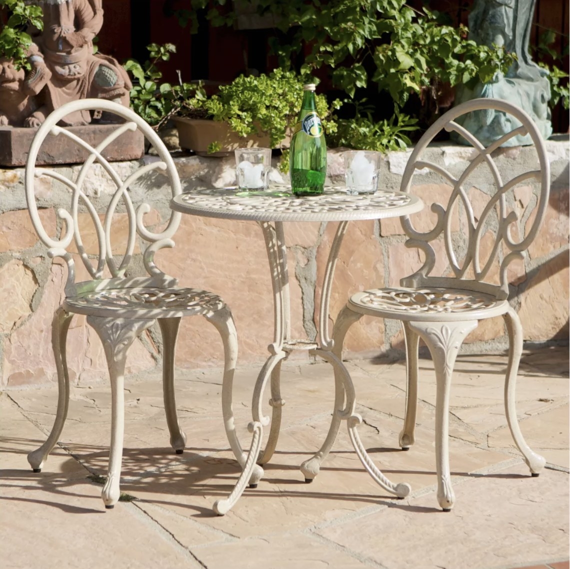 An off-white intricate aluminum table and matching chairs on an outdoor patio