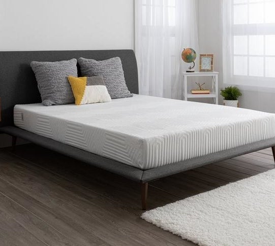 mattress on gray bed frame with pillows on top