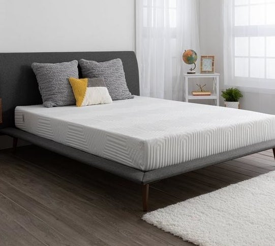 mattress on gray bed frame with pillows on top