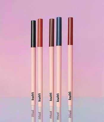 the five underlined eyeliners standing up against an ombre pink background