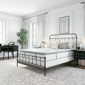 a mattress on top of box spring on top of metal bed frame with headboard and footboard in well decorated white bedroom