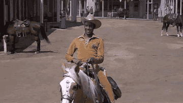 Scene from Blazing Saddles with a &quot;Welcome sheriff&quot; sign as Cleavon Little as Bart rides into town on a horse