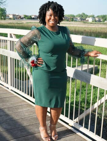 Reviewer in green fitted dress with sheer sleeves