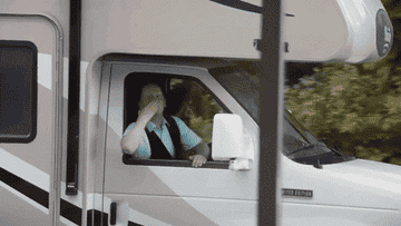 person in an RV blowing kisses and waving
