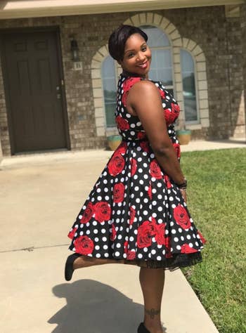 Reviewer wearing red floral and polka dot sleeveless dress 