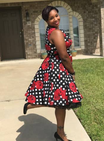 Reviewer wearing red floral and polka dot sleeveless dress 