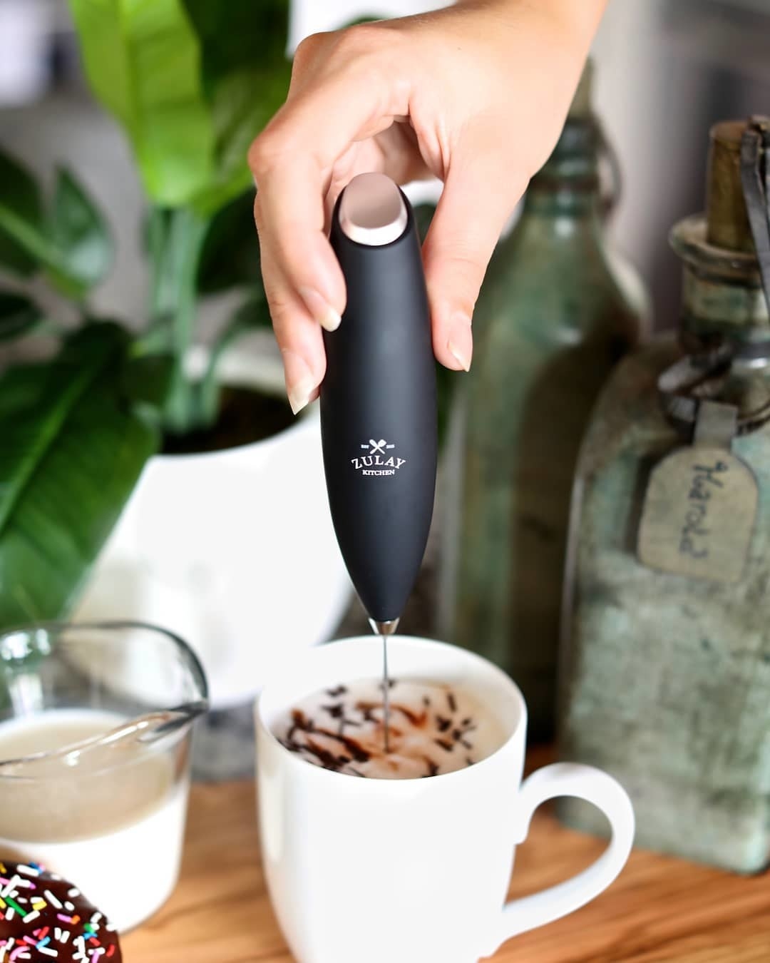 A person using the frother in their coffee