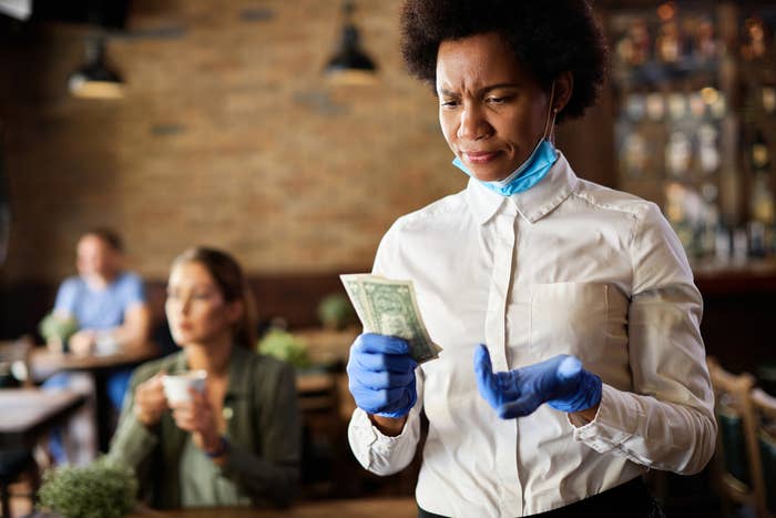 A waitress looking at her tip with confused look on her face