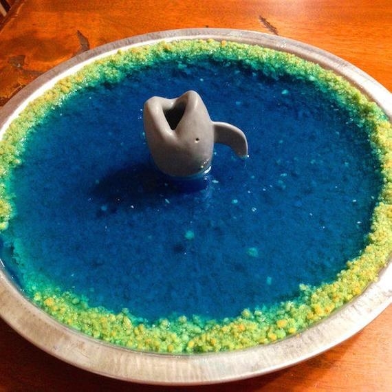 the pie shark sticking out of a pie with blue jelly and sand on the crust 