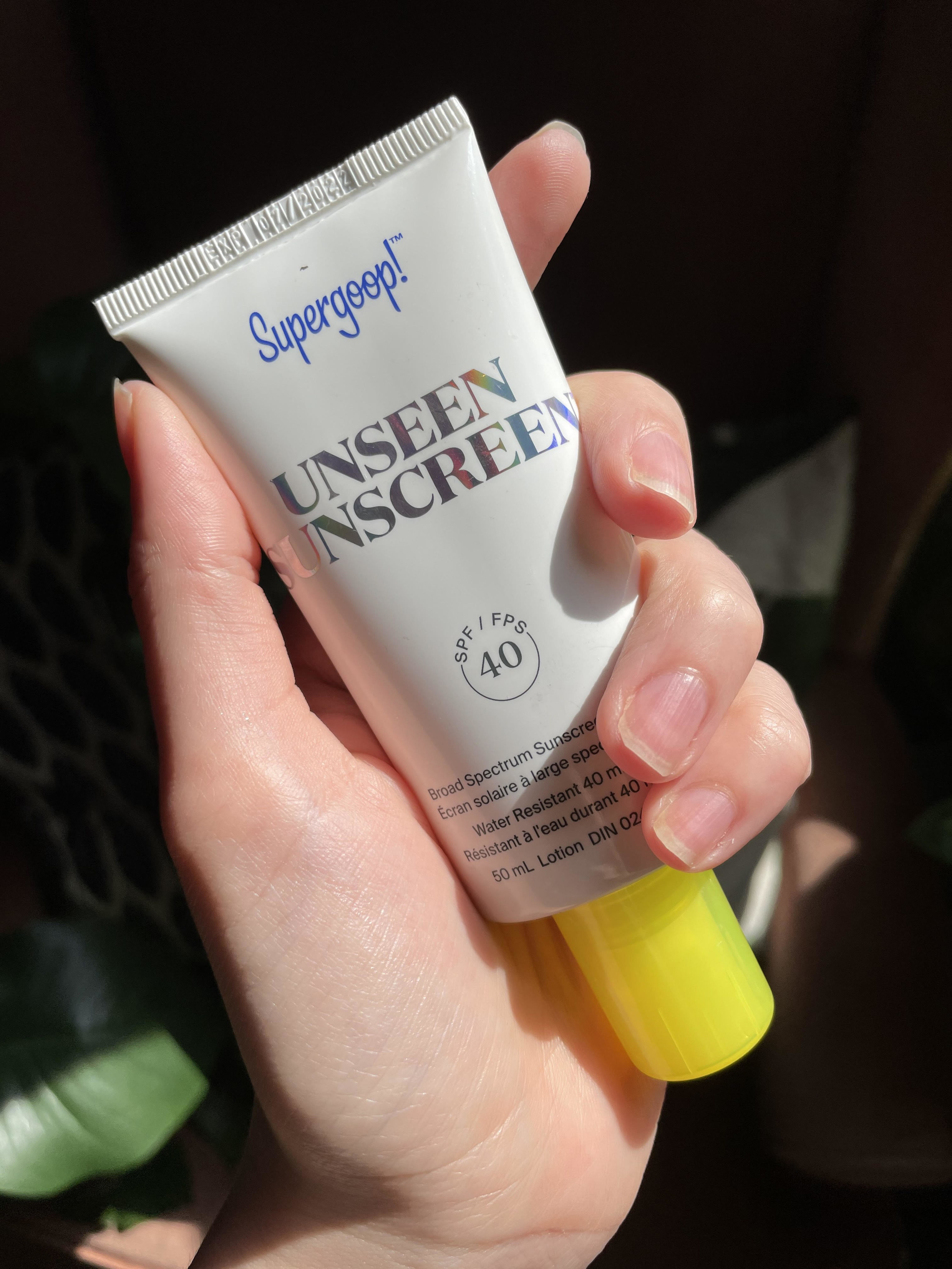 A person holding the tube of sunscreen
