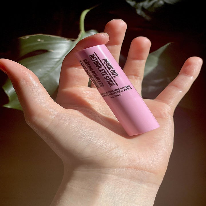 A person holding the closed tube of retinol balm