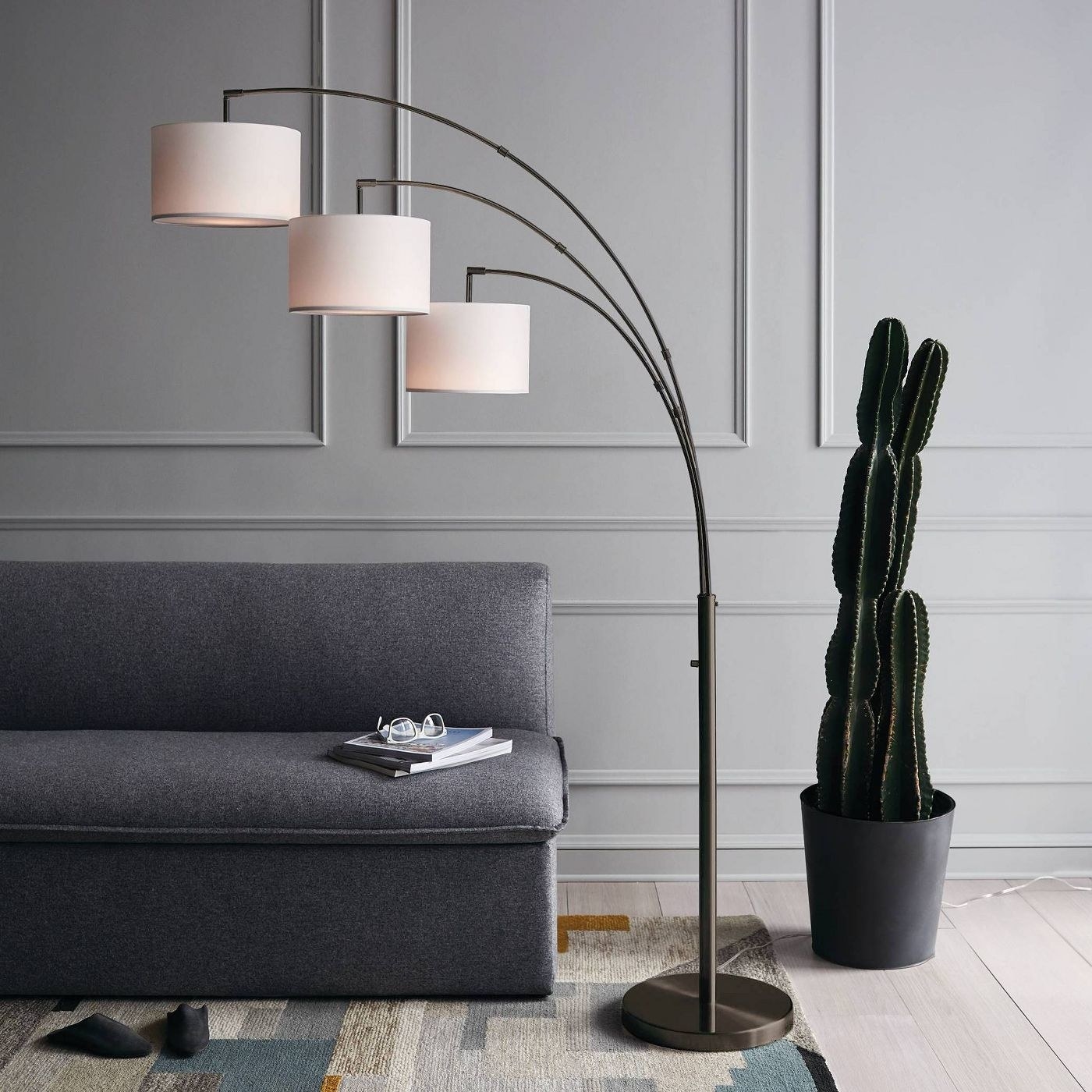 A three part shaded arc floor lamp next to a couch