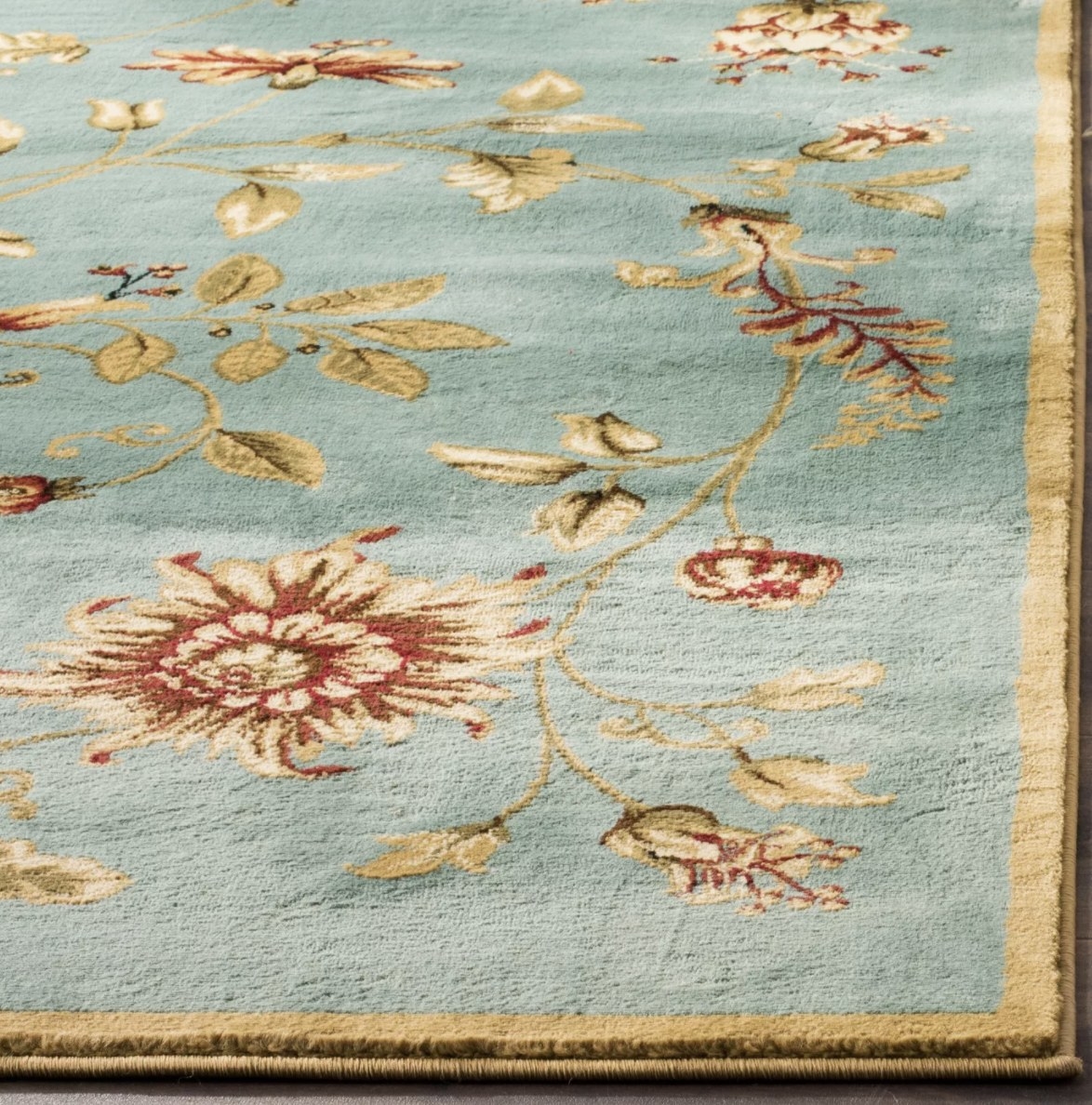 A closeup view of the light blue rug with floral designs