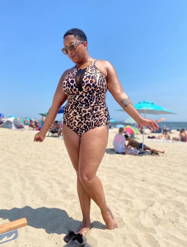 A reviewer wearing the monokini in cheetah print on a beach 