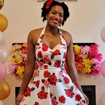 reviewer wearing the dress in white with a red rose print