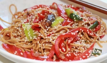 slices of red peppers and noodles on a plate toss with sesame seeds