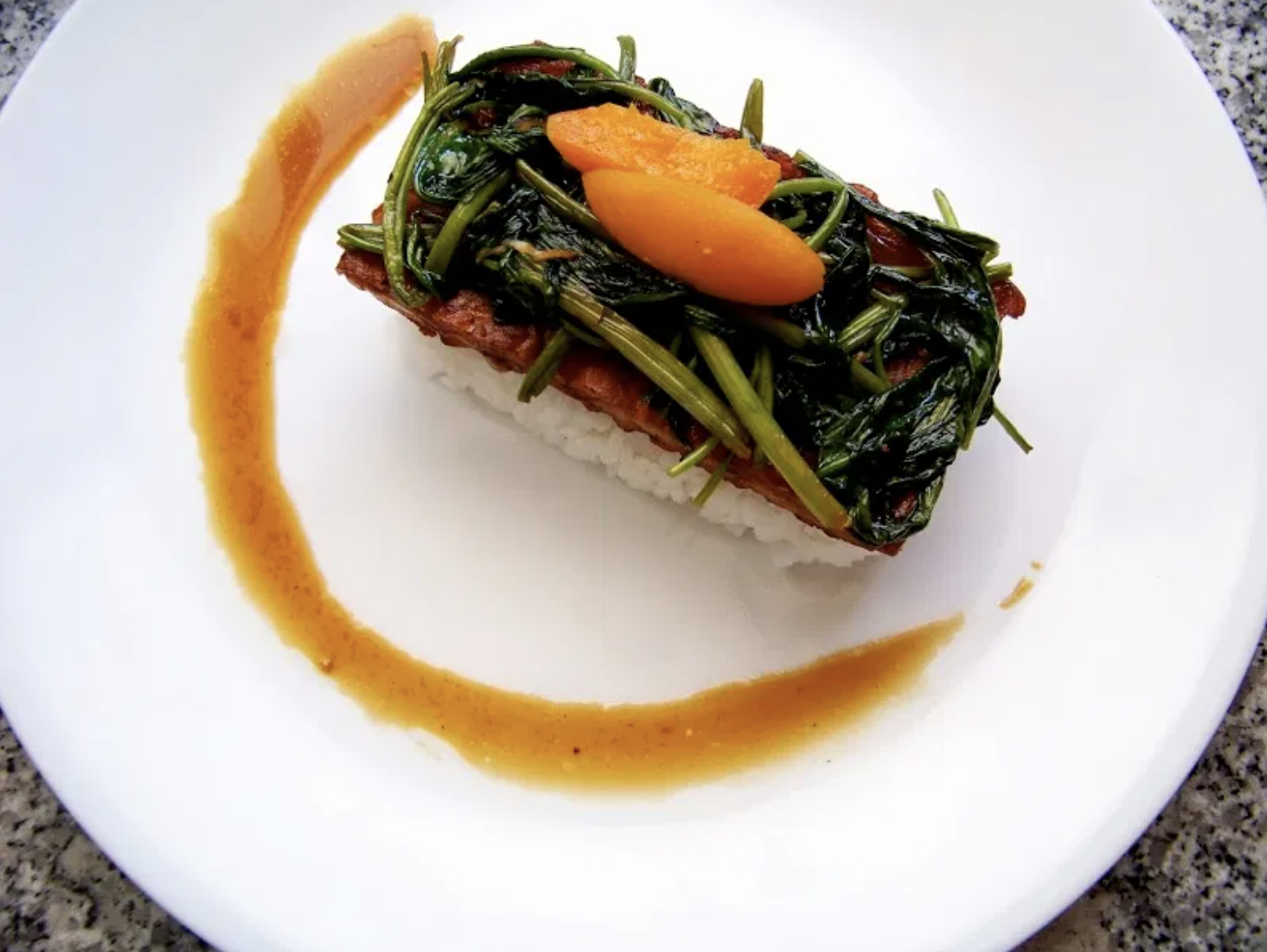 a block of sushi rice with tempeh and greens a top of it arranged in a presentation like you&#x27;d see at a four-star restaurant