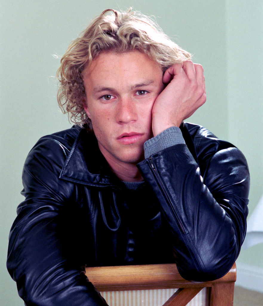 A closeup of Heath Ledger during a photoshoot; he is sitting on a chair and pouting at the camera