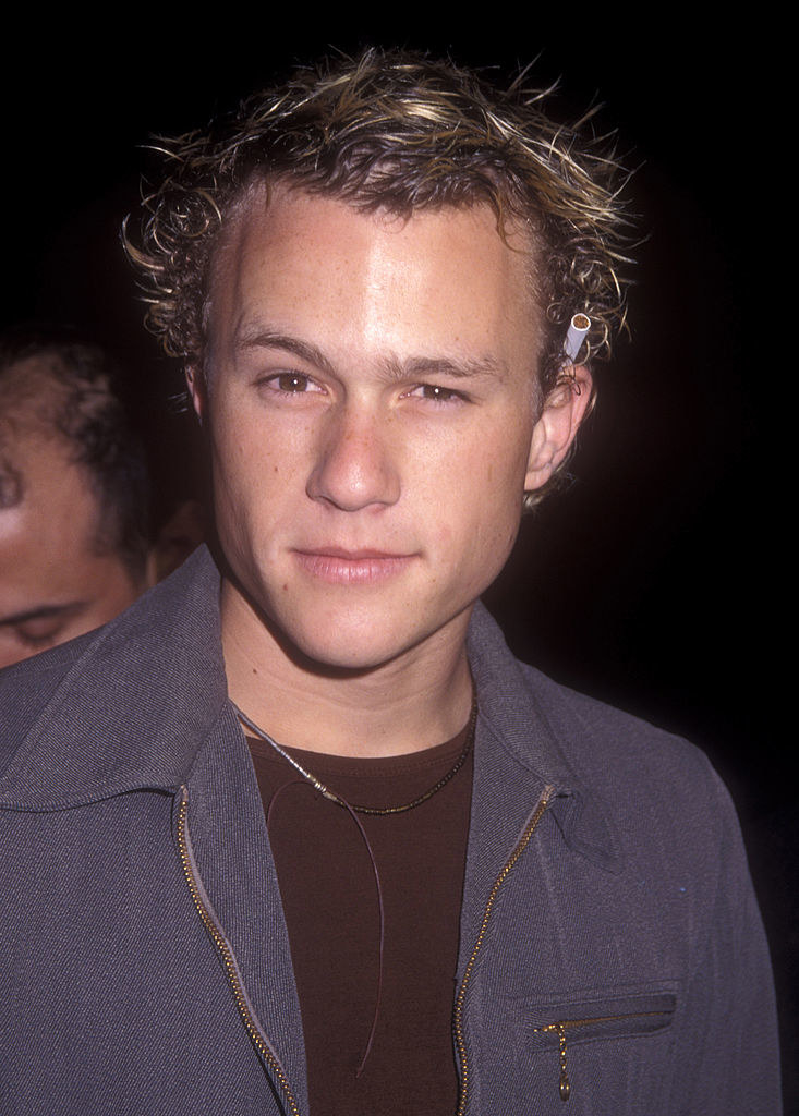 Heath Ledger posing for a photo; he has one eyebrow raised and a cigarette tucked behind his ear