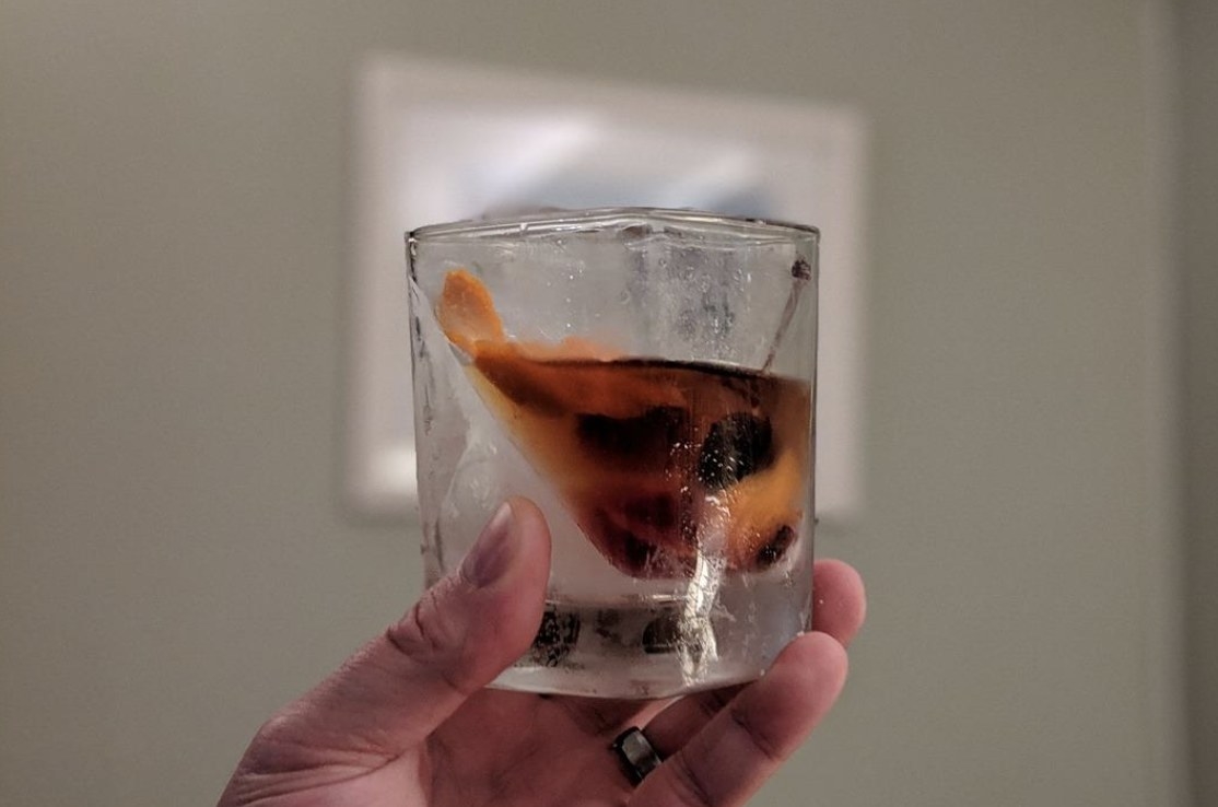 reviewer holding up the glass with half ice, half whiskey 