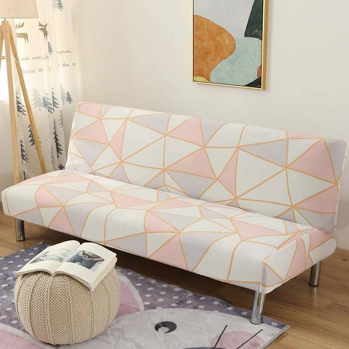 A pink, white and grey slipcover is seen on a couch with clean, golden lines creating unequal triangles and squares.