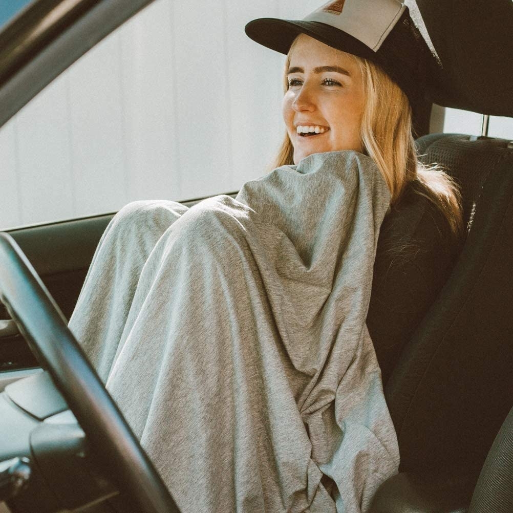A person wearing the blanket in a car