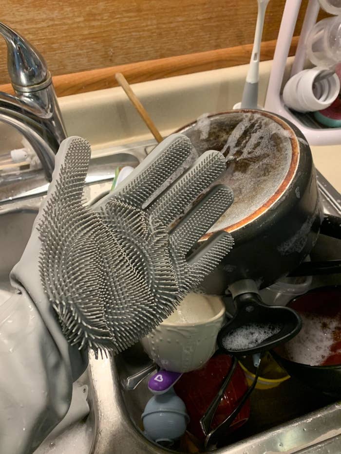 Reviewer wearing the gloves while washing dishes with right hand facing up, showing the bristols on it