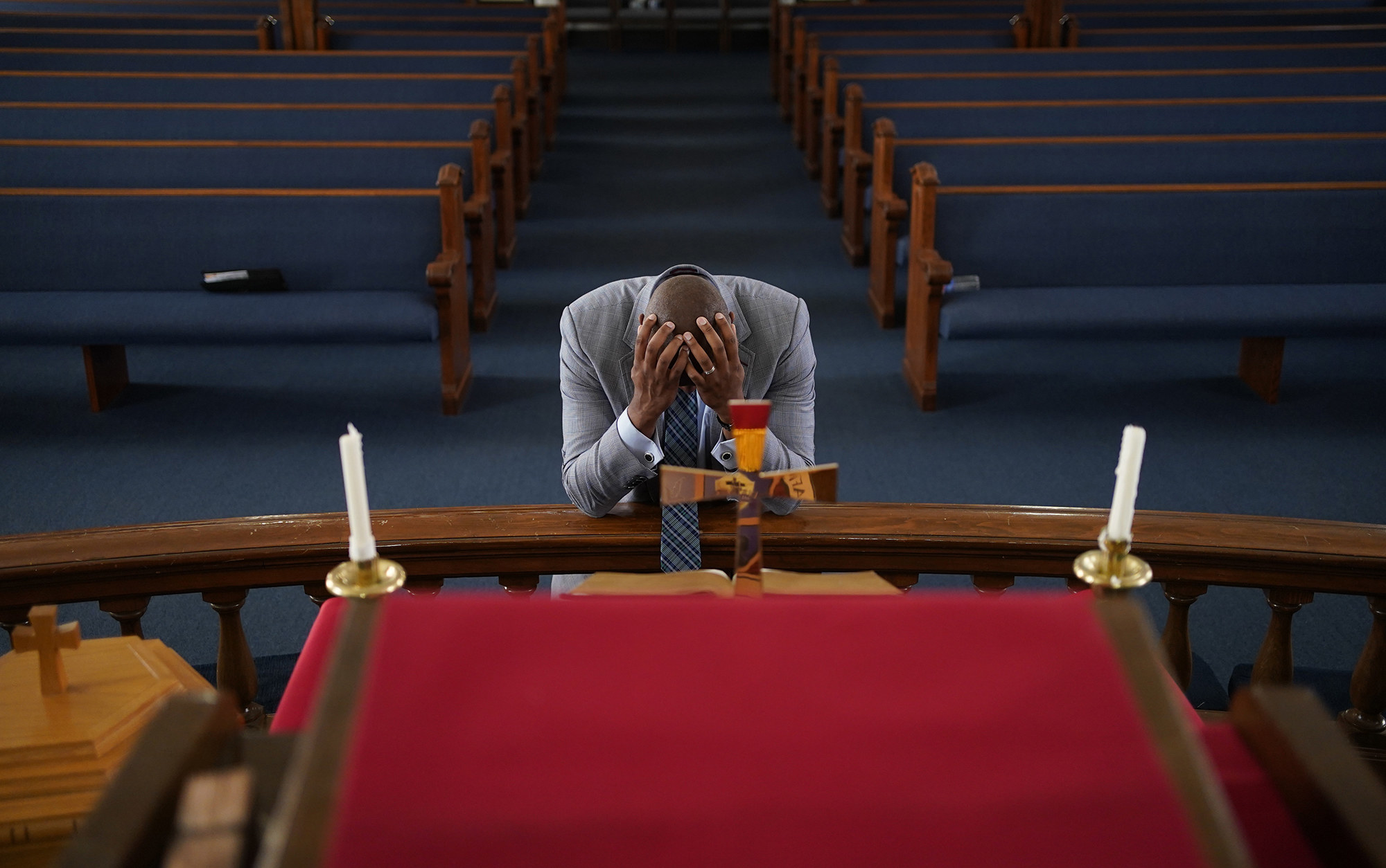 A man prays at an altar with his head in his hands