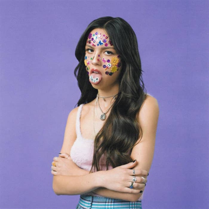 Olivia crossing her arms with a stern expression and stickers all over face