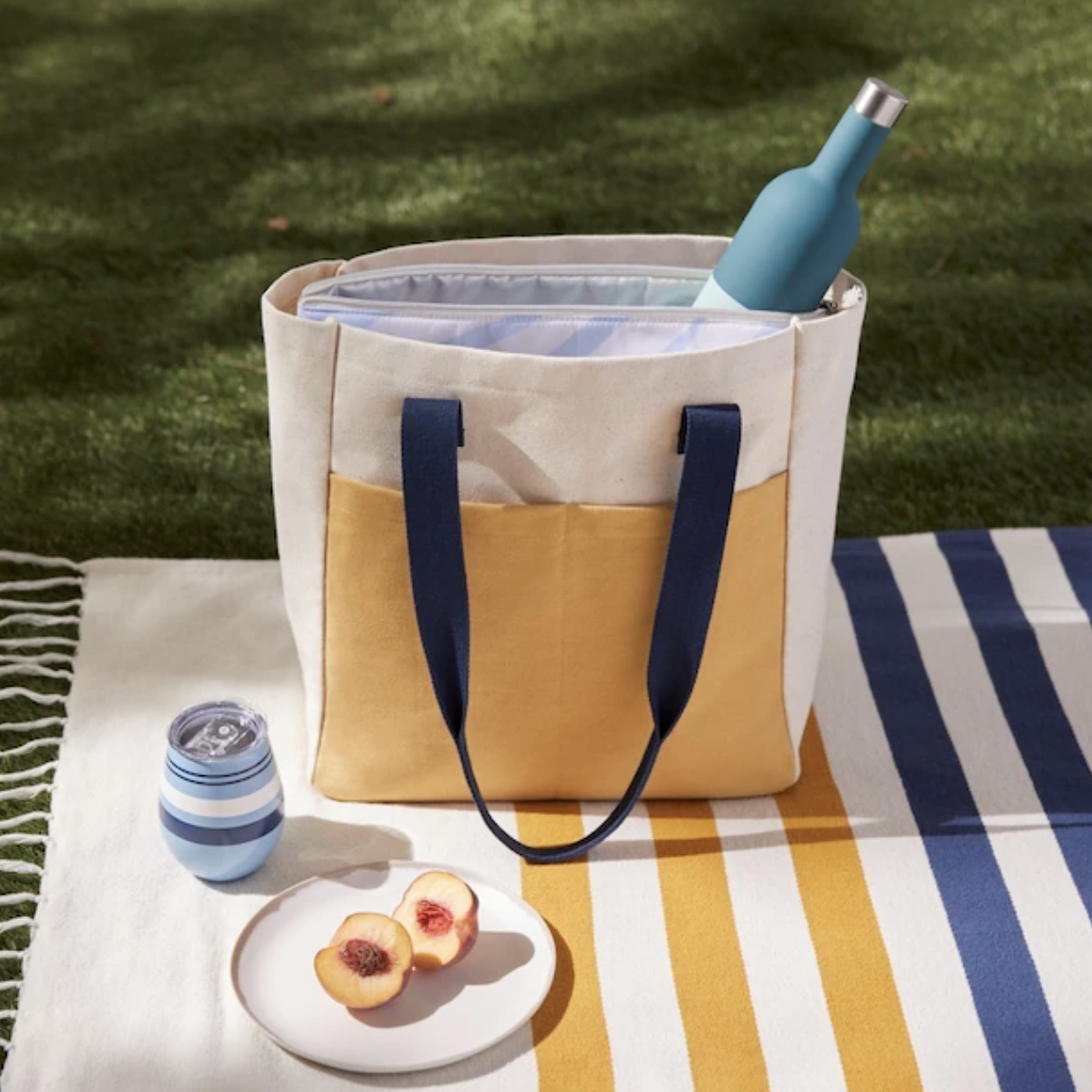 tote with a bottle in it on a towel on the ground