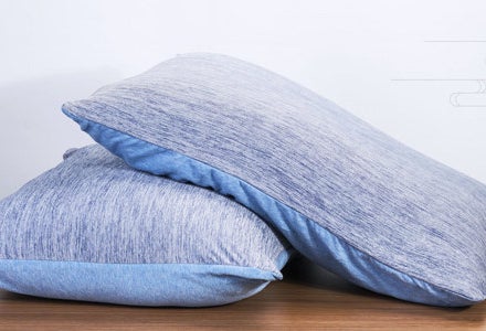 Two pillows with the pillow cases on them on a table
