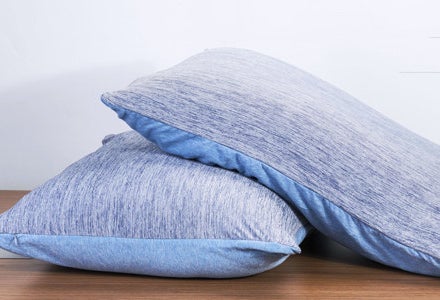 Two pillows with the pillow cases on them on a table