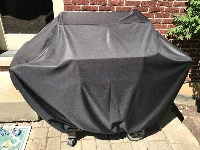 a reviewer's grill covered in a black tarp-like cover
