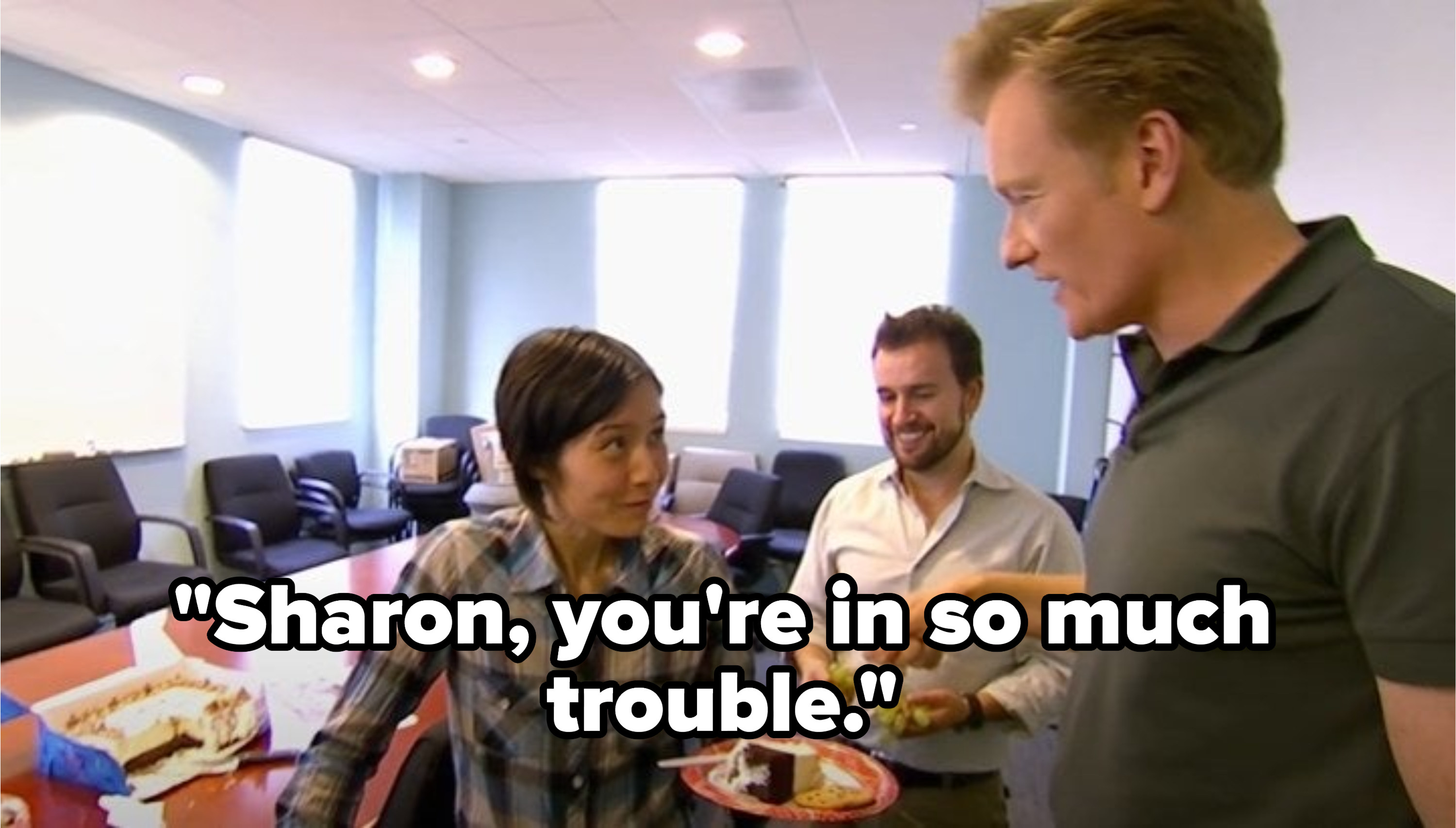 Conan talking to a staff member that's eating cake