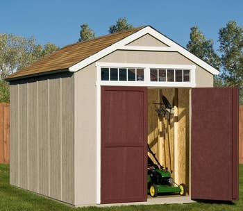 the big storage shed with a shingles on the roof, maroon double doors and windows