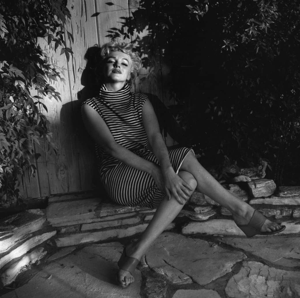 Marilyn Monroe sits outside in a striped dress