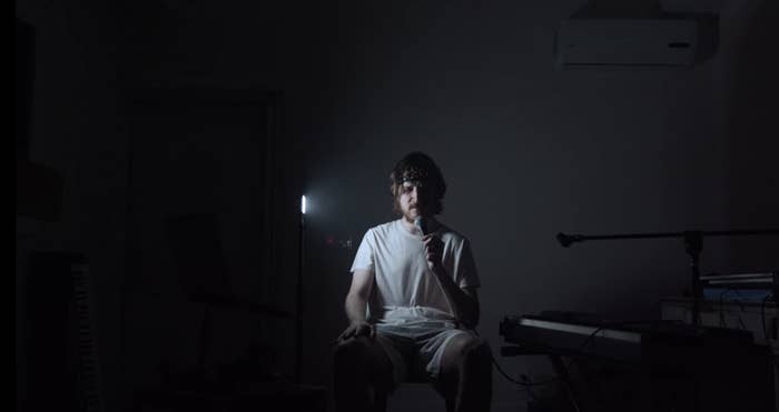 Bo Burnham sitting in a dark room on a chair