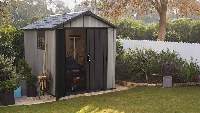 the outdoor shed with a side window, double doors, and a shingle roof