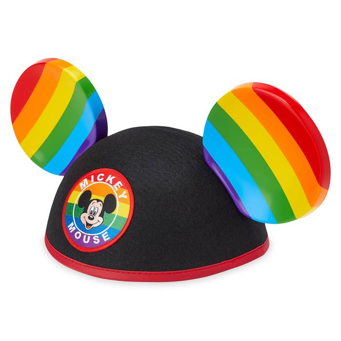 A mickey mouse hat with ears that have rainbow stripes and a mickey mouse patch on the front