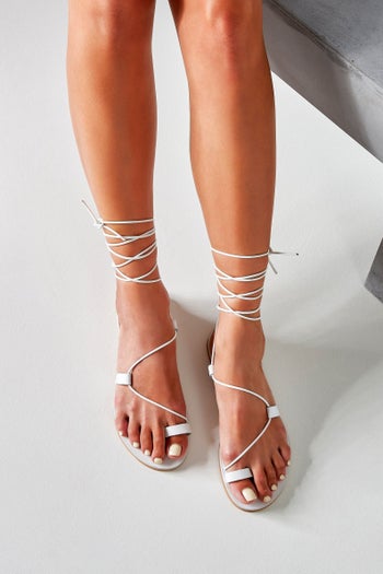 a model wearing the sandals in white
