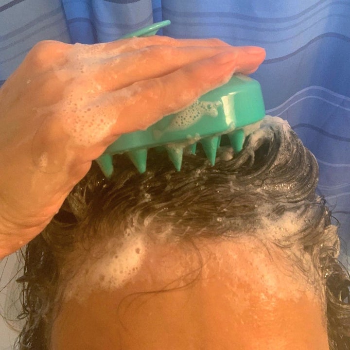 reviewer using a scalp massager in the shower