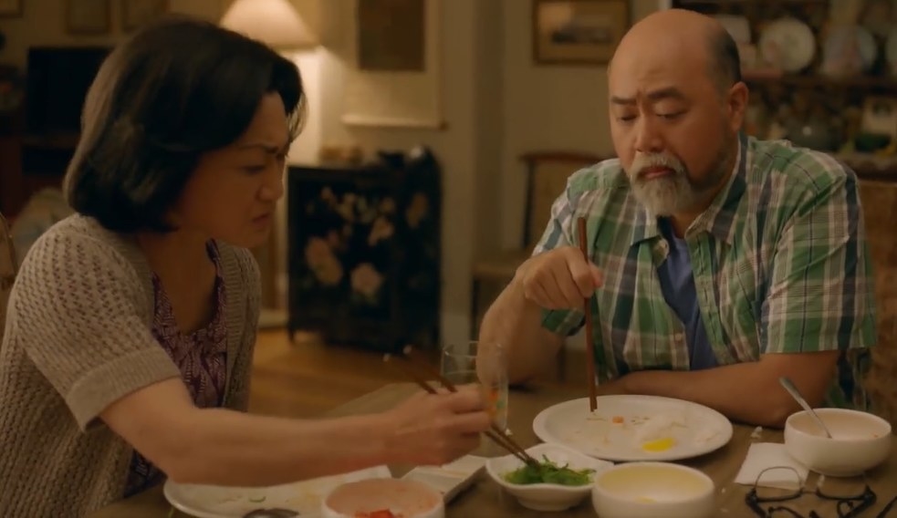 Umma is using her chopsticks to pick up a seaweed side dish while talking to Appa at the table.