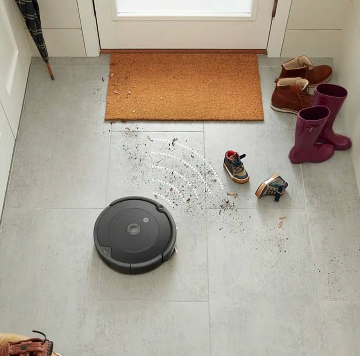 An iRobot Roomba cleaning dirt off the floors in a foyer