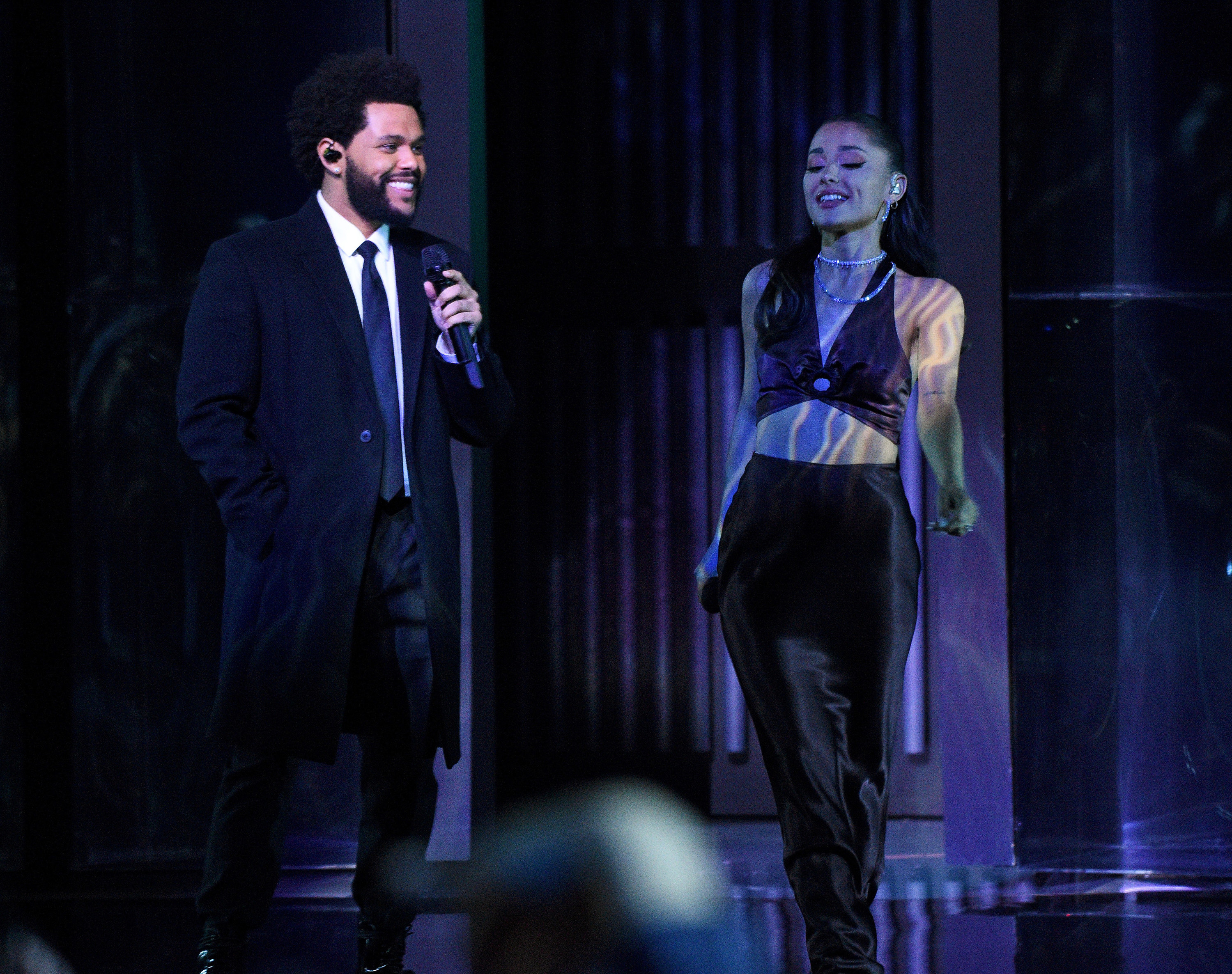 Ariana stands next to The Weeknd while performing