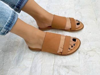 a model wearing the sandals in brown