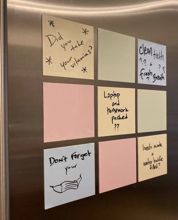 A reviewer photo of the sticky notes in pink, yellow, blue, and green colors on a fridge